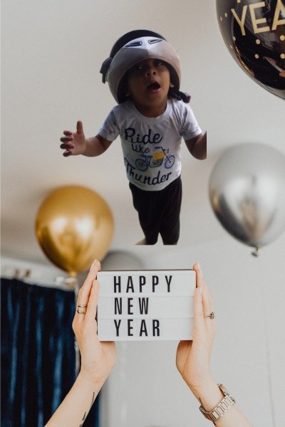 Happy New Year celebration with a playful baby in the air and festive balloons