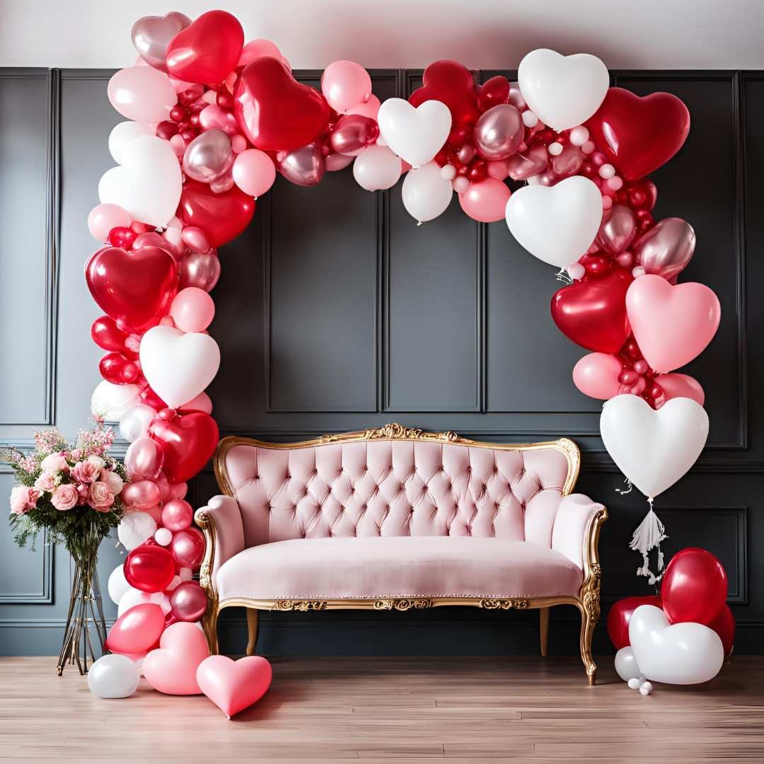 Valentine’s Day photo booth with heart balloon arch and pink sofa